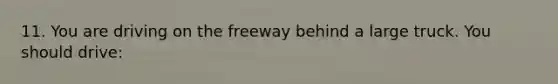 11. You are driving on the freeway behind a large truck. You should drive: