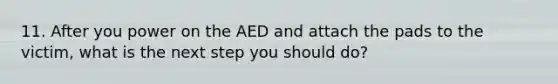 11. After you power on the AED and attach the pads to the victim, what is the next step you should do?