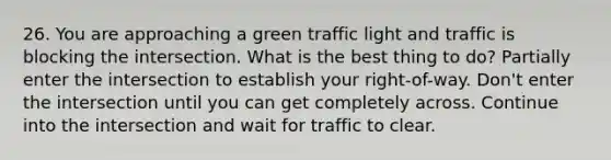 26. You are approaching a green traffic light and traffic is blocking the intersection. What is the best thing to do? Partially enter the intersection to establish your right-of-way. Don't enter the intersection until you can get completely across. Continue into the intersection and wait for traffic to clear.