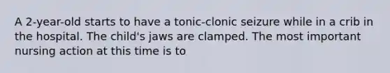 A 2-year-old starts to have a tonic-clonic seizure while in a crib in the hospital. The child's jaws are clamped. The most important nursing action at this time is to