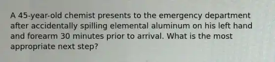 A 45-year-old chemist presents to the emergency department after accidentally spilling elemental aluminum on his left hand and forearm 30 minutes prior to arrival. What is the most appropriate next step?