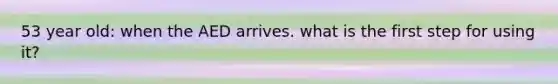 53 year old: when the AED arrives. what is the first step for using it?