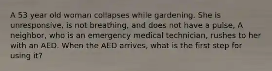 A 53 year old woman collapses while gardening. She is unresponsive, is not breathing, and does not have a pulse, A neighbor, who is an emergency medical technician, rushes to her with an AED. When the AED arrives, what is the first step for using it?