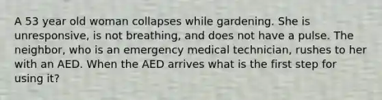 A 53 year old woman collapses while gardening. She is unresponsive, is not breathing, and does not have a pulse. The neighbor, who is an emergency medical technician, rushes to her with an AED. When the AED arrives what is the first step for using it?