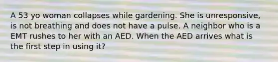 A 53 yo woman collapses while gardening. She is unresponsive, is not breathing and does not have a pulse. A neighbor who is a EMT rushes to her with an AED. When the AED arrives what is the first step in using it?