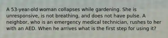 A 53-year-old woman collapses while gardening. She is unresponsive, is not breathing, and does not have pulse. A neighbor, who is an emergency medical technician, rushes to her with an AED. When he arrives what is the first step for using it?