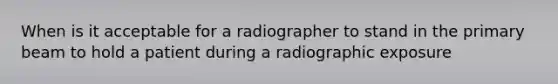 When is it acceptable for a radiographer to stand in the primary beam to hold a patient during a radiographic exposure