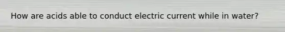 How are acids able to conduct electric current while in water?