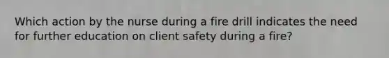 Which action by the nurse during a fire drill indicates the need for further education on client safety during a fire?