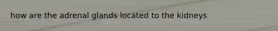 how are the adrenal glands located to the kidneys