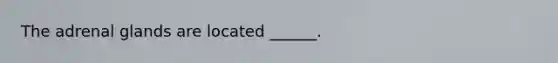 The adrenal glands are located ______.