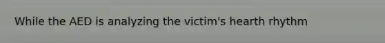 While the AED is analyzing the victim's hearth rhythm