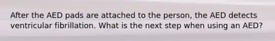 After the AED pads are attached to the person, the AED detects ventricular fibrillation. What is the next step when using an AED?