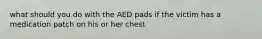 what should you do with the AED pads if the victim has a medication patch on his or her chest