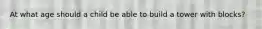 At what age should a child be able to build a tower with blocks?