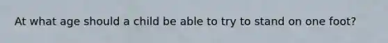 At what age should a child be able to try to stand on one foot?