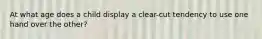 At what age does a child display a clear-cut tendency to use one hand over the other?