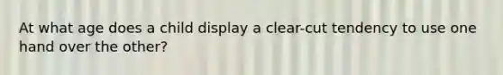 At what age does a child display a clear-cut tendency to use one hand over the other?