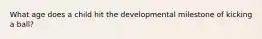 What age does a child hit the developmental milestone of kicking a ball?