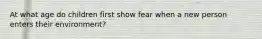 At what age do children first show fear when a new person enters their environment?