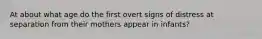 At about what age do the first overt signs of distress at separation from their mothers appear in infants?