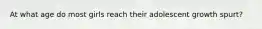 At what age do most girls reach their adolescent growth spurt?