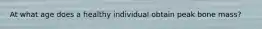 At what age does a healthy individual obtain peak bone mass?