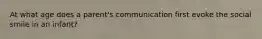 At what age does a parent's communication first evoke the social smile in an infant?