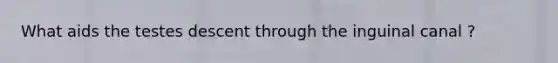 What aids the testes descent through the inguinal canal ?