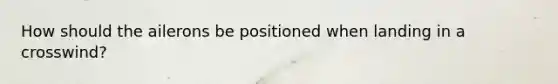 How should the ailerons be positioned when landing in a crosswind?