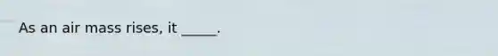 As an air mass rises, it _____.