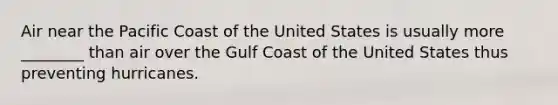 Air near the Pacific Coast of the United States is usually more ________ than air over the Gulf Coast of the United States thus preventing hurricanes.