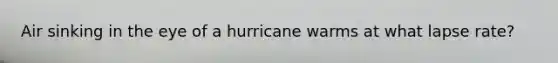 Air sinking in the eye of a hurricane warms at what lapse rate?