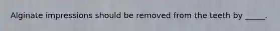 Alginate impressions should be removed from the teeth by _____.