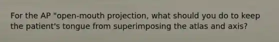 For the AP "open-mouth projection, what should you do to keep the patient's tongue from superimposing the atlas and axis?