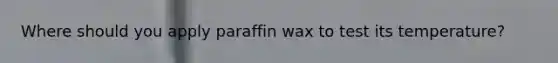 Where should you apply paraffin wax to test its temperature?