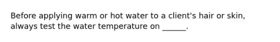 Before applying warm or hot water to a client's hair or skin, always test the water temperature on ______.