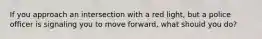 If you approach an intersection with a red light, but a police officer is signaling you to move forward, what should you do?
