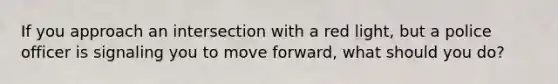 If you approach an intersection with a red light, but a police officer is signaling you to move forward, what should you do?