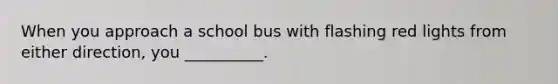 When you approach a school bus with flashing red lights from either direction, you __________.