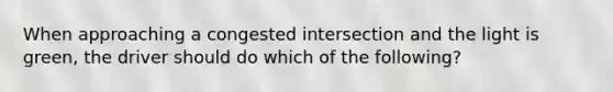 When approaching a congested intersection and the light is green, the driver should do which of the following?