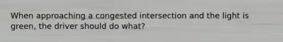 When approaching a congested intersection and the light is green, the driver should do what?