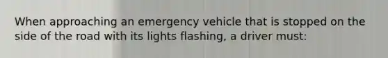 When approaching an emergency vehicle that is stopped on the side of the road with its lights flashing, a driver must: