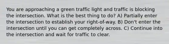 You are approaching a green traffic light and traffic is blocking the intersection. What is the best thing to do? A) Partially enter the intersection to establish your right-of-way. B) Don't enter the intersection until you can get completely across. C) Continue into the intersection and wait for traffic to clear.