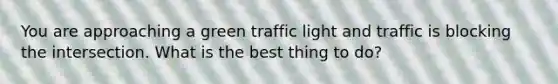 You are approaching a green traffic light and traffic is blocking the intersection. What is the best thing to do?