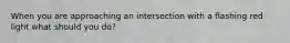 When you are approaching an intersection with a flashing red light what should you do?