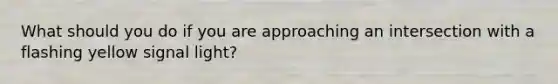 What should you do if you are approaching an intersection with a flashing yellow signal light?