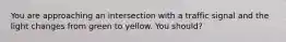 You are approaching an intersection with a traffic signal and the light changes from green to yellow. You should?