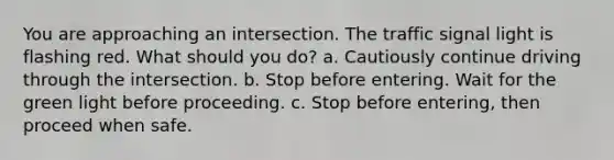 You are approaching an intersection. The traffic signal light is flashing red. What should you do? a. Cautiously continue driving through the intersection. b. Stop before entering. Wait for the green light before proceeding. c. Stop before entering, then proceed when safe.