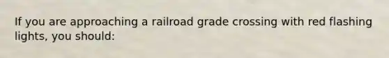 If you are approaching a railroad grade crossing with red flashing lights, you should: